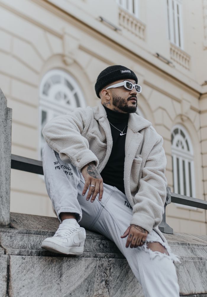Stylish man in casual wear sits on urban steps, showcasing contemporary fashion.